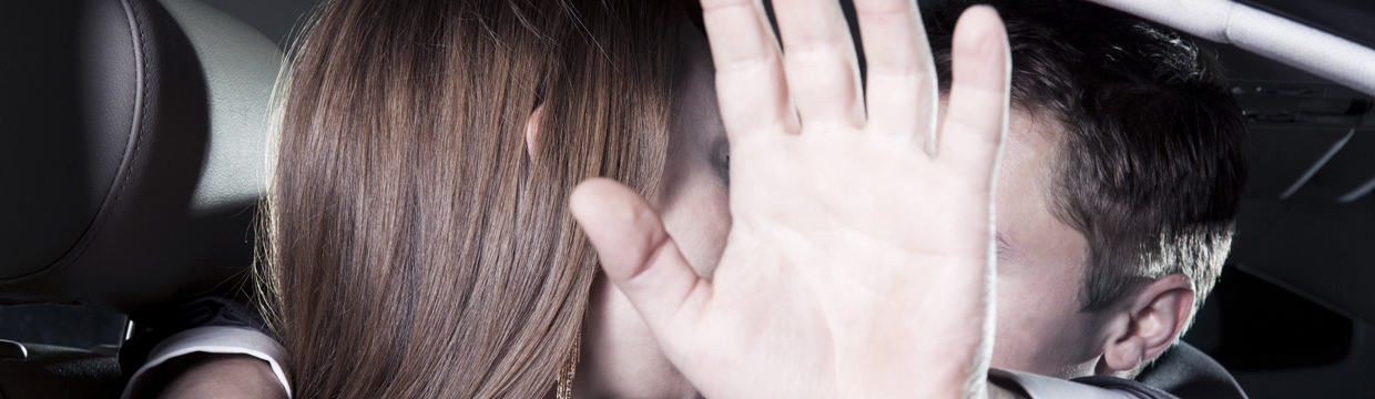 Paparazzi fotografieren ein Paar im Auto, das sich mit einer Hand abzuschirmen versucht